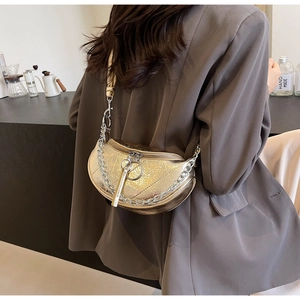 Detailed close-up of metallic gold crescent bag with pleated texture and silver chain