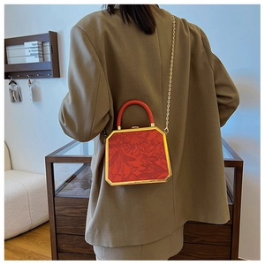 Detail of red embossed floral box bag with gold metal trim and elegant chain strap
