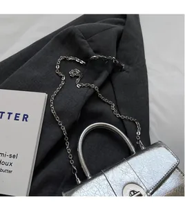 Close-up of silver cracked leather handbag with metallic chain and rotary lock detail