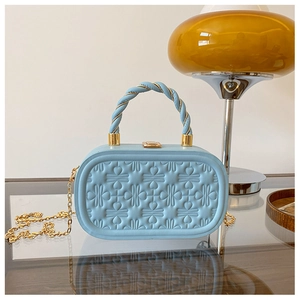 Detalle del bolso caja azul claro con corazones en relieve y asa trenzada elegante