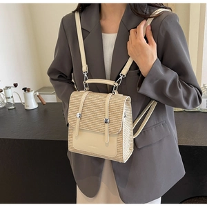 Detail showing versatile woven straw and cream leather backpack worn over a grey blazer