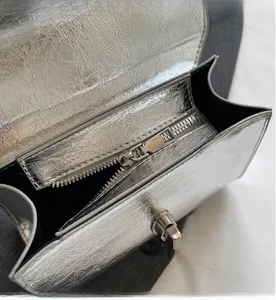 Detail of silver metallic leather bag showing smooth zipper and metal turn-lock buckle