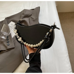 Detail of black PU leather shoulder bag featuring large pearls and silver heart charms