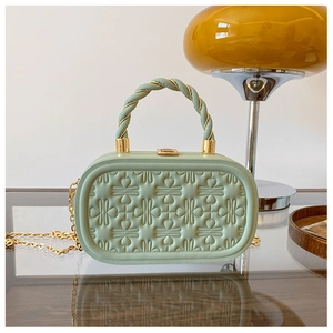 Detalle del bolso rígido verde menta con grabados en relieve y cadena dorada