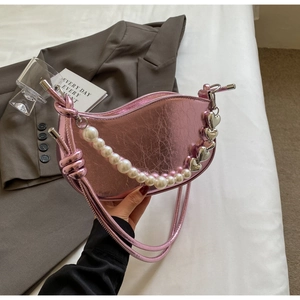 Detail of pink metallic crescent bag with pearl handle and silver heart charm decoration