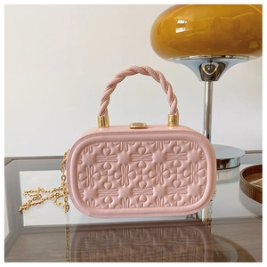 Detalle de bolso caja rosa con textura de corazones en relieve y cadena dorada fina
