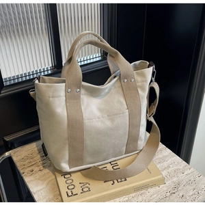 Dettaglio borsa tote in tela con manici a contrasto e accenti di rivetti in metallo