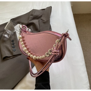 Detail of metallic pink saddle bag featuring pearl handle and heart metal charm