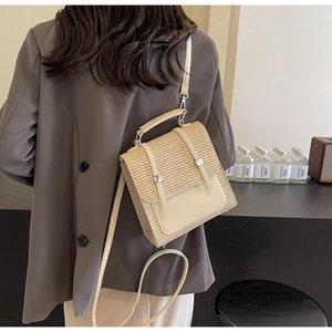 Detail of minimalist straw crossbody bag with cream leather flap and adjustable strap