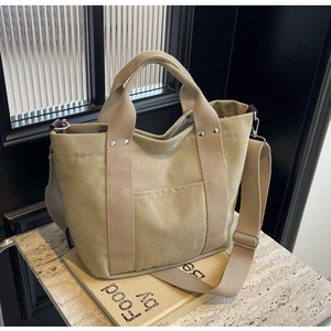 Dettaglio borsa tote in tela kaki con tracolla regolabile e borchie argentate