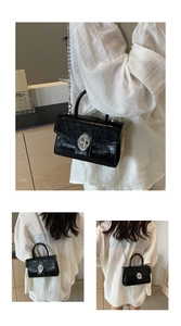 Close-up of black patent leather crossbody bag featuring a silver twist lock and chain
