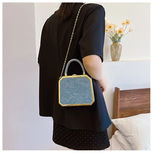 Detail of blue box bag with 3D floral embossing and elegant gold metal frame