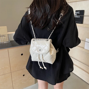 Eleganter weißer gesteppter Mini-Rucksack mit Kettengurt an einem Model im Raum