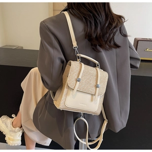 Detail of light beige straw woven backpack featuring adjustable leather straps and top handle