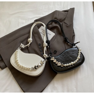 Detail of embossed leather crescent underarm bags with pearl heart chains on a blazer