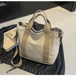 Dettaglio della borsa tote in tela beige con manici marroni e tasca frontale