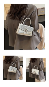 Macro view of silver patent leather handbag with vintage crackle texture and metal lock