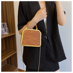 Detail view of octagon box bag with floral embossing and gold chain shoulder strap