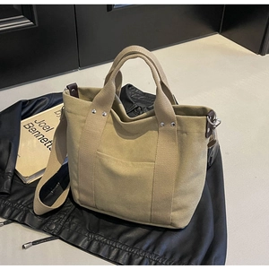 Dettaglio della borsa tote in tela kaki con rivetti in metallo e tracolla regolabile
