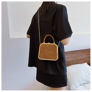 Brown leather crossbody bag with floral embossing and gold chain shown on a model