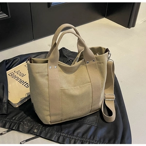 Dettaglio della borsa tote in tela kaki con tracolla regolabile su giacca di pelle