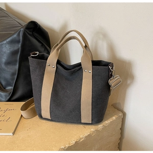 Dettaglio della borsa in tela grigio scuro con cinghie crema e robusti anelli a D in metallo