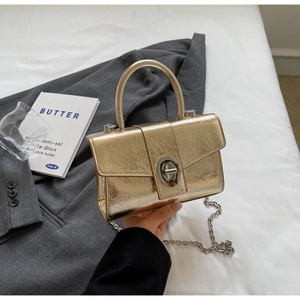 Detail of gold cracked leather mini square bag with silver metal lock and chain strap