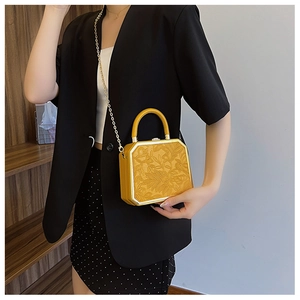 Detail of yellow box bag with floral embossing and gold chain strap for women