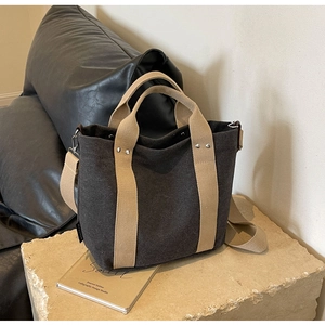 Vista dettagliata della borsa tote grigia su piedistallo con manici beige e tracolla