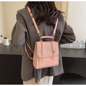Detail of pink straw backpack with leather flap and woven texture worn by model