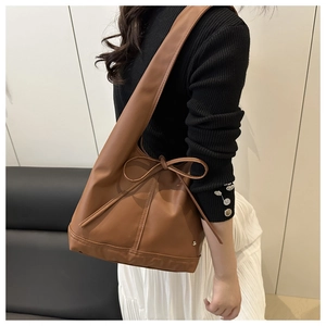 Detailaufnahme der braunen Ledertasche mit Schleifendekor und Metallnieten