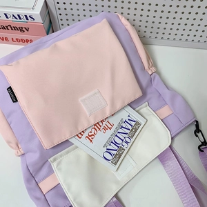 Détail d'un sac à dos en toile rose et violet avec poche interne et livres scolaires