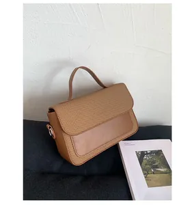 Detail of a brown patchwork crossbody bag featuring woven fabric and smooth leather texture