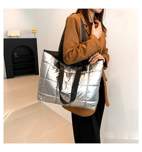 Detalle del bolso tote acolchado plateado con correas negras y acabado metálico