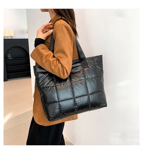 Detalle de un bolso shopper acolchado negro con acabado brillante y costuras de cuadros