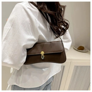 Detail view of a vintage dark brown leather baguette bag with a golden horseshoe buckle clasp