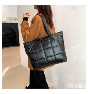 Bolso tote acolchado negro con textura acolchada y correa ancha para el hombro en modelo real