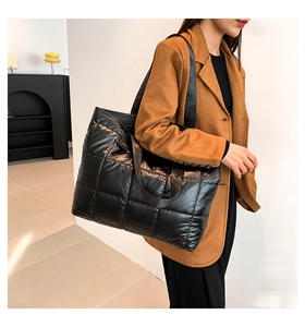 Primer plano de un bolso tote acolchado negro con textura de nailon y diseño de rejilla grande
