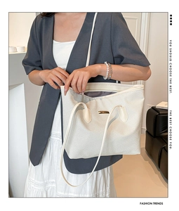 Dettaglio dell'elegante borsa tote intrecciata color crema con tracolla e fibbia dorata