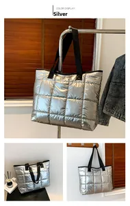 Detalle del bolso tote plateado acolchado con costuras cuadradas y correas de tela negra