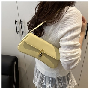 Dettaglio di una borsa a spalla in pelle giallo chiaro con chiusura in metallo dorato