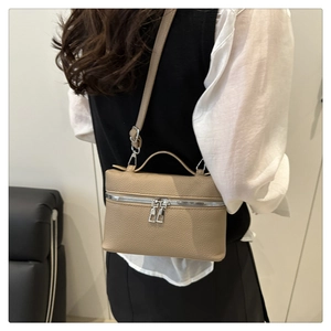 Crossbody view of a khaki litchi grain leather mini bag with silver hardware on model