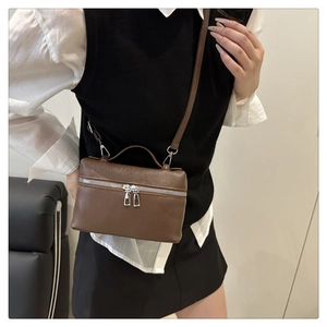 Detail of a brown lychee pattern leather handbag with silver zippers and a top handle