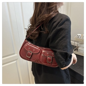 Detail of burgundy glossy leather shoulder bag with decorative silver buckles on pockets