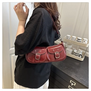 Détail du sac bandoulière en cuir verni bordeaux avec boucles argentées et chaîne