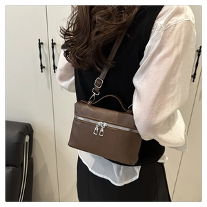 Close-up of brown pebbled leather handbag with double silver zipper and handle