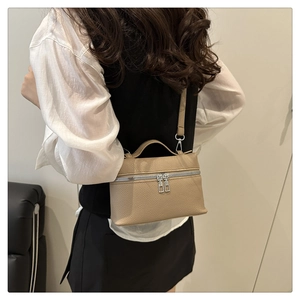Detail of minimalist beige pebble leather vanity bag with silver zippers and handle