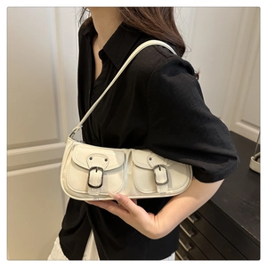 Detail view of cream white patent leather shoulder bag with vintage metal buckles