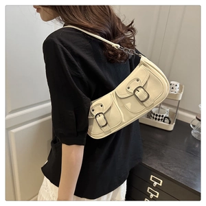 Detail of cream faux leather shoulder bag featuring dual pockets and vintage metal buckles