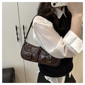 Close-up of a vintage brown baguette bag with two front pockets and silver metal buckles